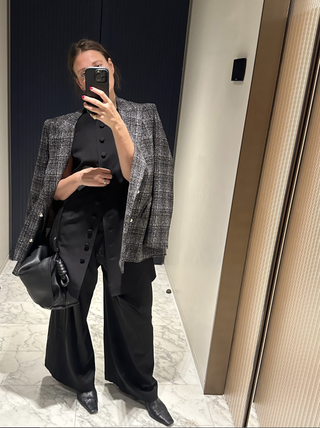 Sara Holzman wears a tailored black set with a plaid blazer