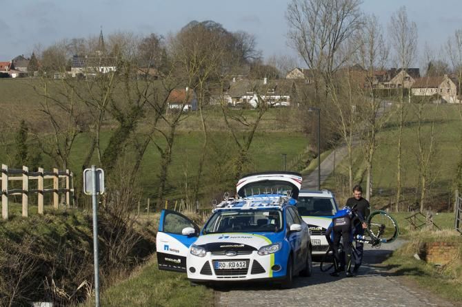 A NetApp-Endura rider changes out a flat tire at his team car.