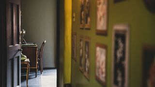 An olive coloured hallway with pictures on the wall