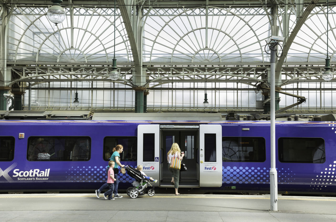 Four passengers entering a ScotRail train, a woman by herself and then a mother pushing a pushchair with her daughter