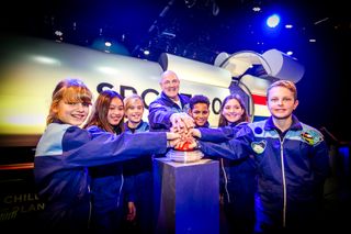 Dutch astronaut André Kuipers (center) with children, outside the SpaceBuzz "spacecraft." Thousands of kids have experienced the virtual reality show so far.