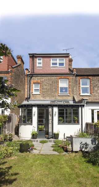 Curved wall and metal-framed windows on a white extension to the rear of the property