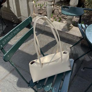 Tas bahu Freja berwarna putih di kursi taman.