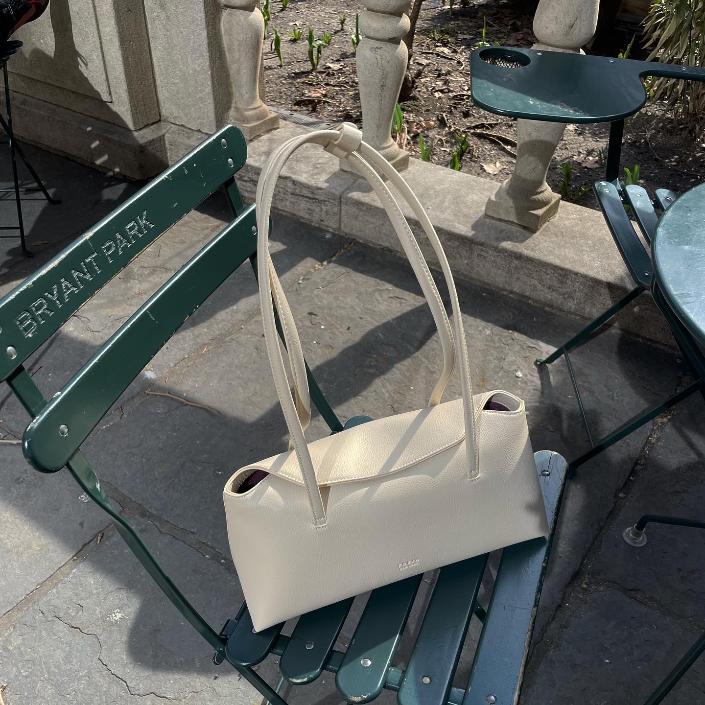 A Freja off-white shoulder bag on a park chair.