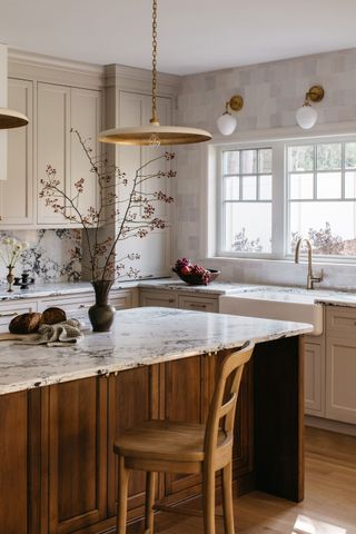 a neutral kitchen with a wood island and marble backsplash