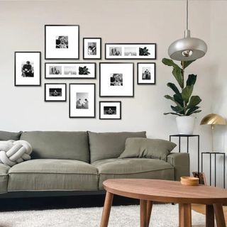 A black and white gallery wall with frames from Wayfair above a green sofa
