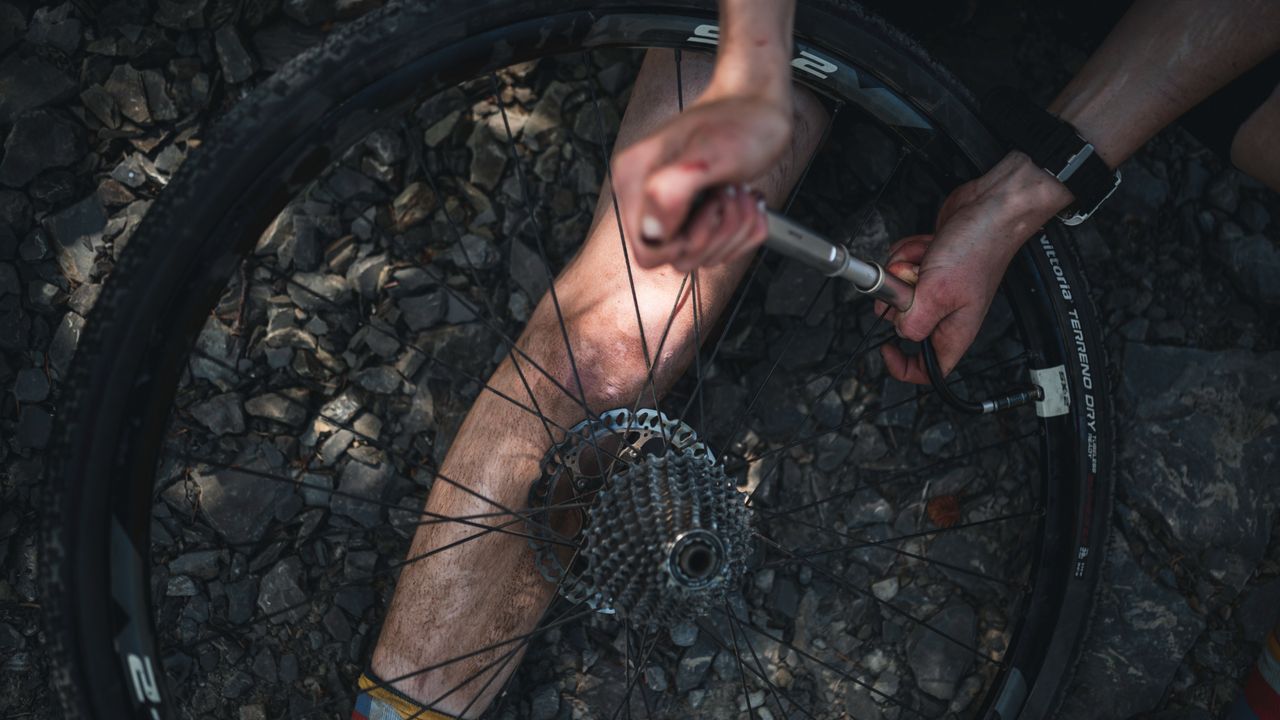 A cyclist repairs a puncture at the side of the road