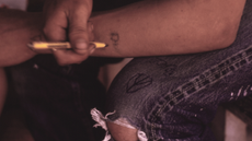 Young man doodles on his jeans and his arm with an ink pen.