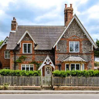 gable roof house with wooden fence adjacent to road