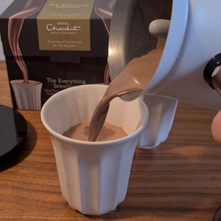 Pouring hot chocolate into a mug standing on kitchen counter