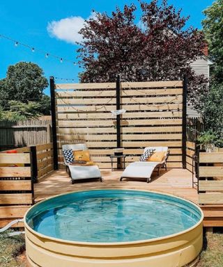 yellow painted stock tank pool with deck and privacy fence