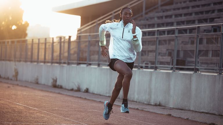 Fit female athlete sprinting on a derelict-looking running track wearing the Polar Pacer Pro running watch