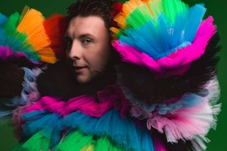 Joe Lycett posed and wearing multi-coloured outfit for Late Night Lycett.