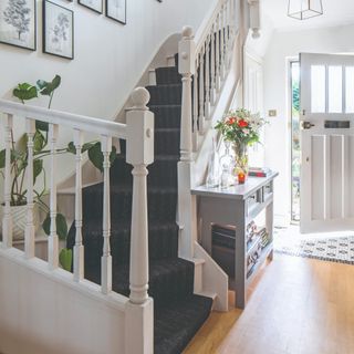 A hallway with a white staircase covered in a striped black runner rug