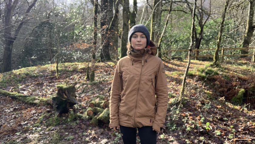 A hiker in the woods wearing the Sasta Peski jacket