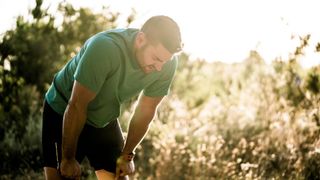 A man panting for breath bent over after a run