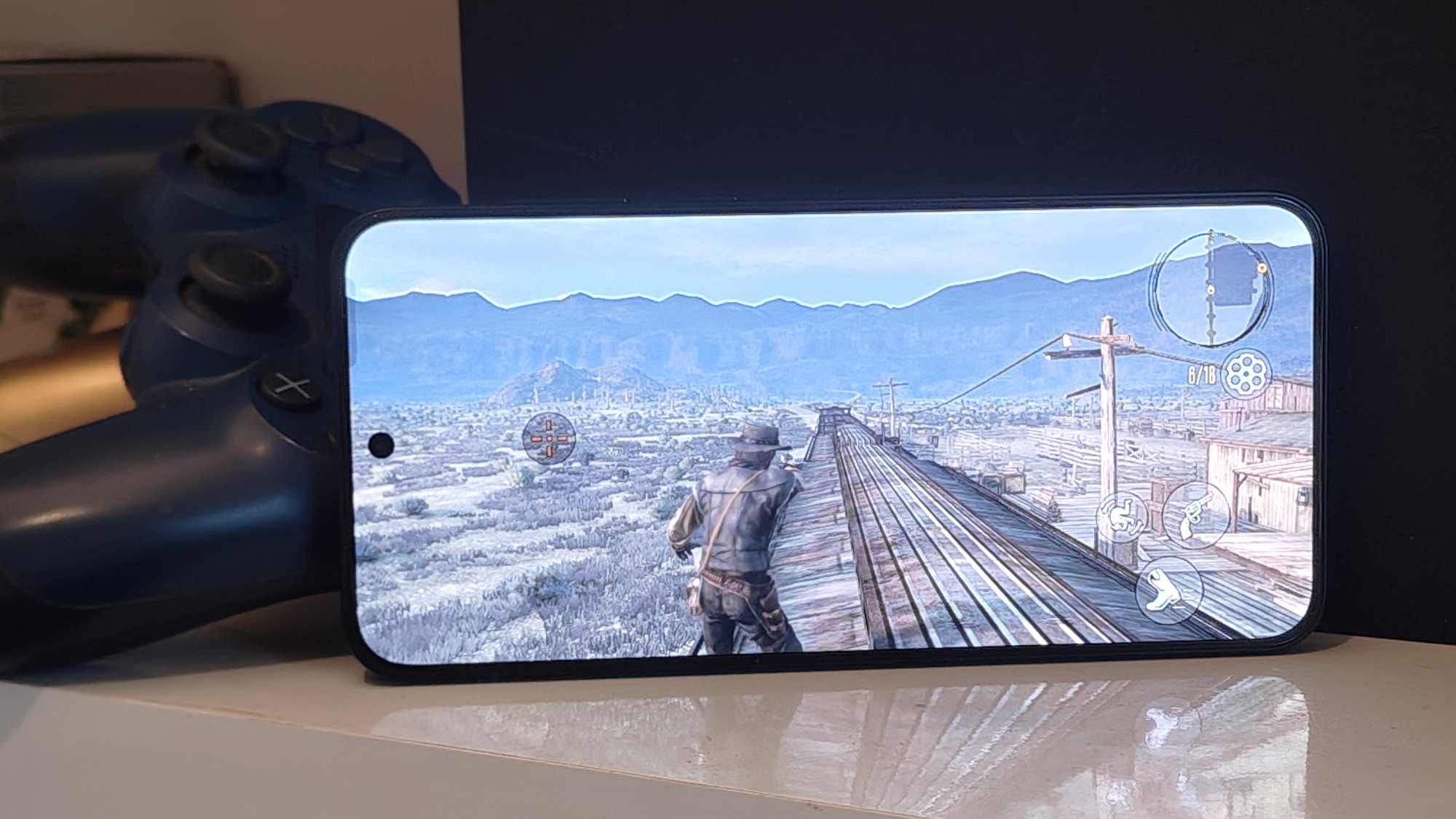 Red Dead Redemption playing on an Android phone, with a PS4 and controllers in the background.