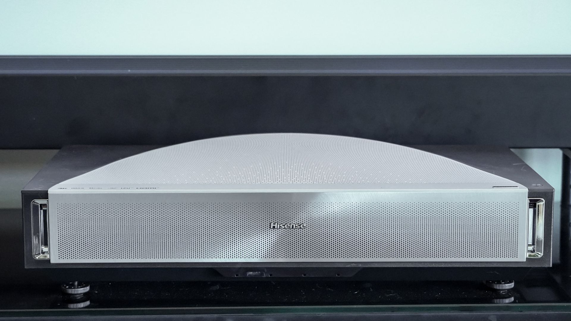 A Hisense PX4 Pro projector on a home media center shelf