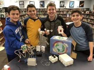 Four boys smiling with weather station