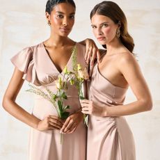 Two models wearing satin bridesmaid dresses sold at Coast holding flowers