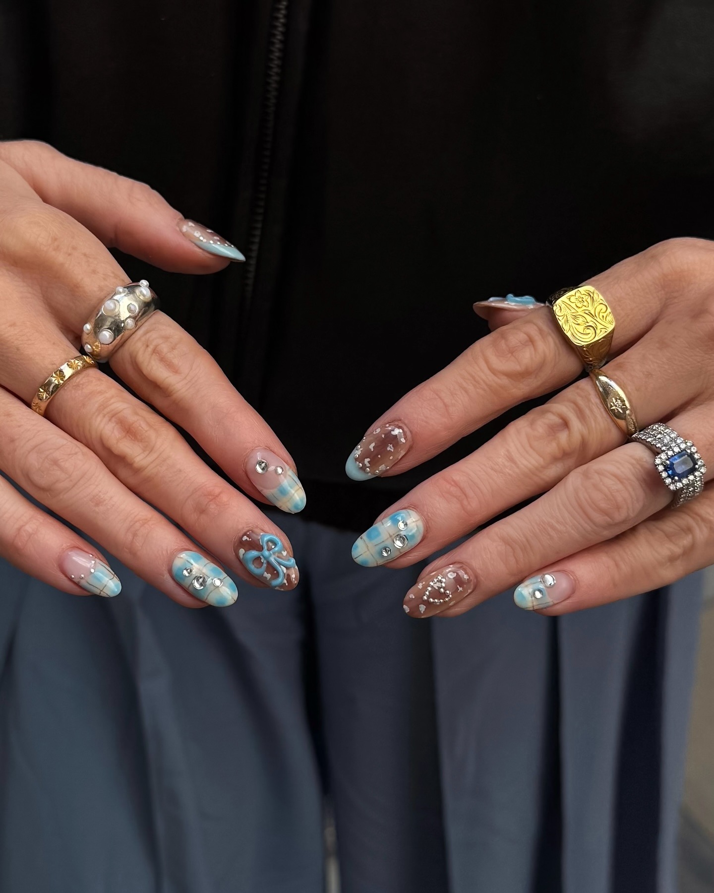 A picture of a woman's hands wearing lots of rings with blue and brown nail art