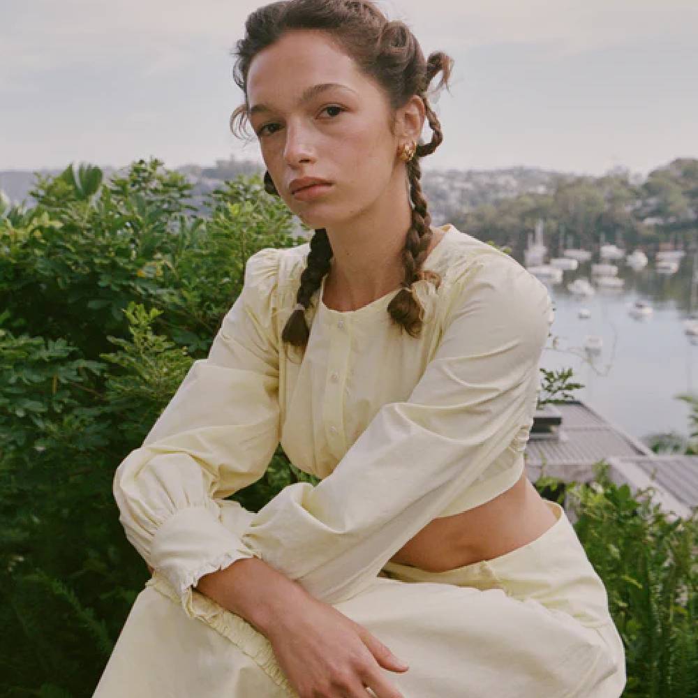 A model wearing a matching yellow long-sleeve linen crop top with a yellow, linen skirt from My Mum Made It. 