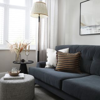 Living room with grey/blue sofa and round grey footstool