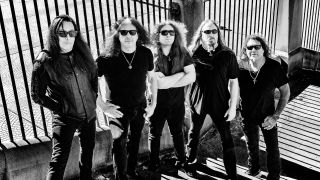 Testament standing against a wall looking very serious