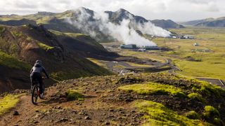 Jenny Graham descends down a mountain path towards an Icelandic renewable energy facility