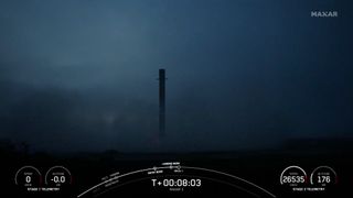 A black and white spacex falcon 9 rocket first stage sits on a landing pad.