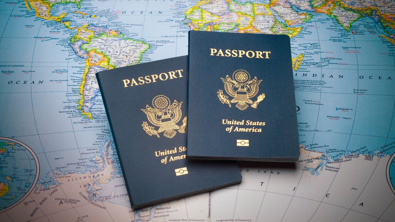 Two blue U.S. passports on top of a colorful world map