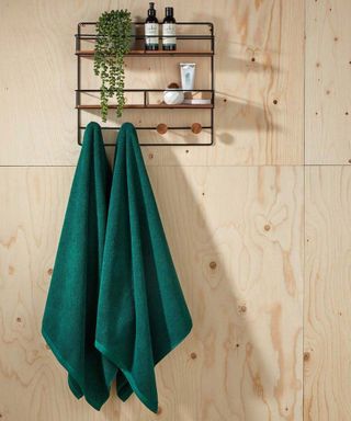 Green towels by Christy hanging on black rack