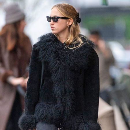 Lila Moss wear a fur coat with black jeans and sunglasses.