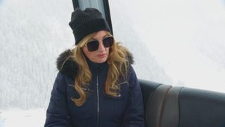 Karren Brady in a warm jacket, hat and sunglasses against a snowy back drop.