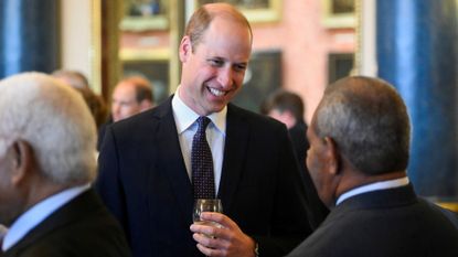 Prince William with a drink in hand at a reception