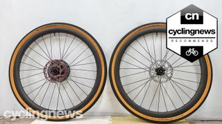 A pair of VeloElite Carbon 350 Gravel disc wheels leaning against a white wall, with a 'recommends' badge overlaid
