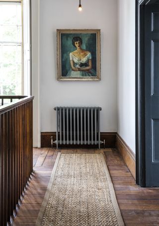 Landing with floorboards with runner, white walls and artwork on wall
