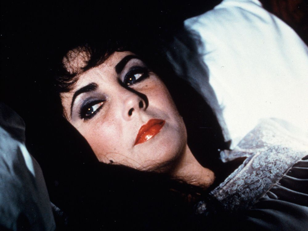 Elizabeth Taylor laying on a pillow in full make-up