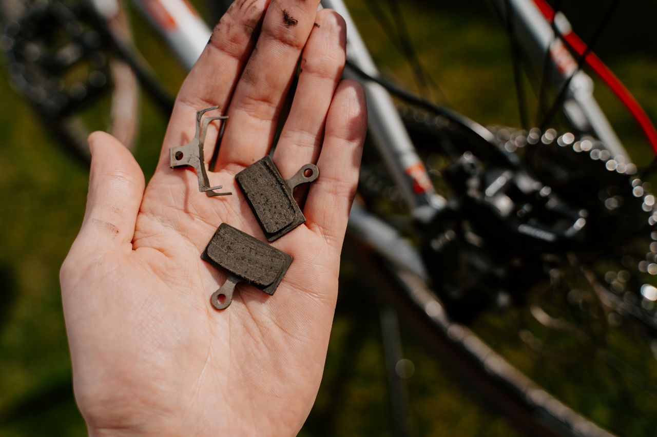 man holding Worn brake pads in front on his bike