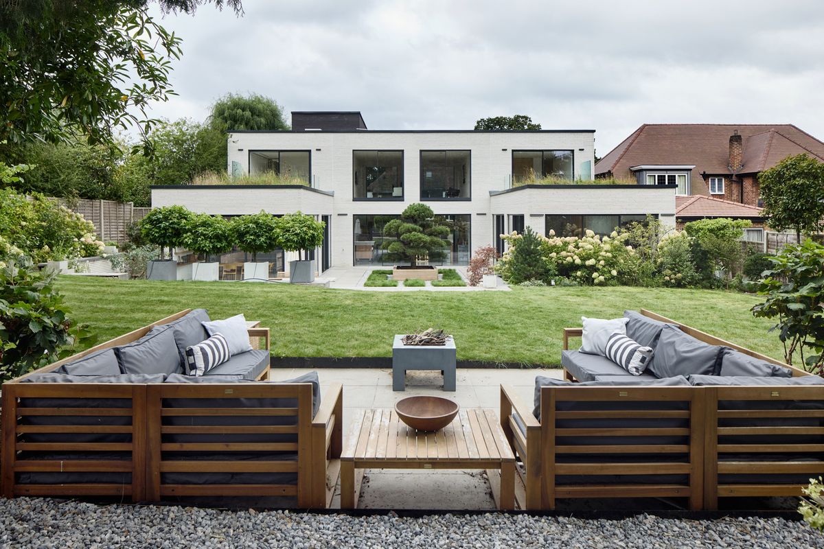A seating area with a fireplace at the back of a garden looking over a raised garden