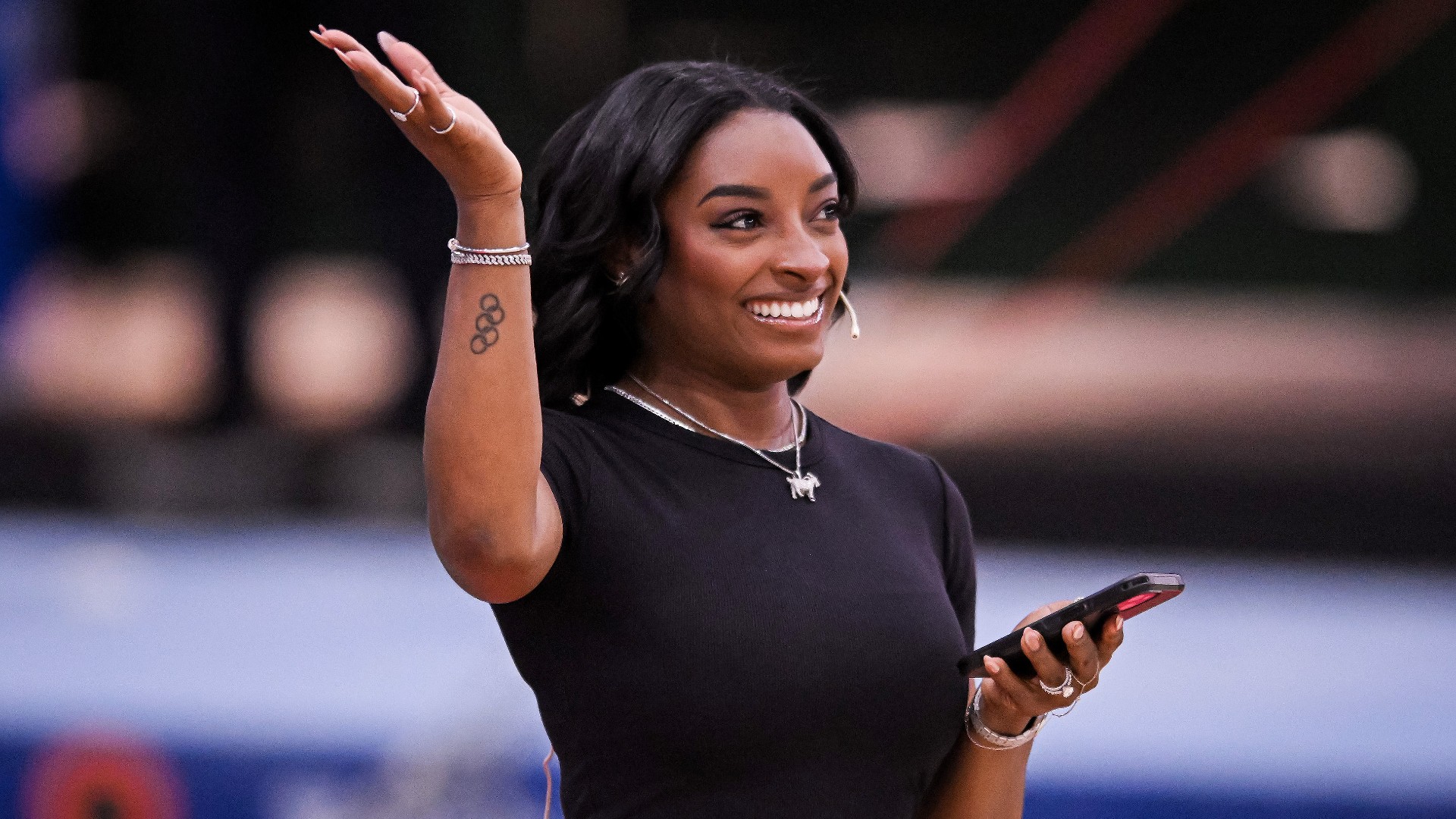 a black woman with short, dark hair wearing a black t-shirt and raising her right hand