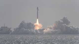 A rocket launch in China. Smoke billows from a ship at sea as a rocket lifts into the sky.