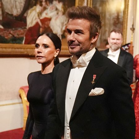 David and Victoria Beckham walking next to each other wearing a black gown and tuxedo