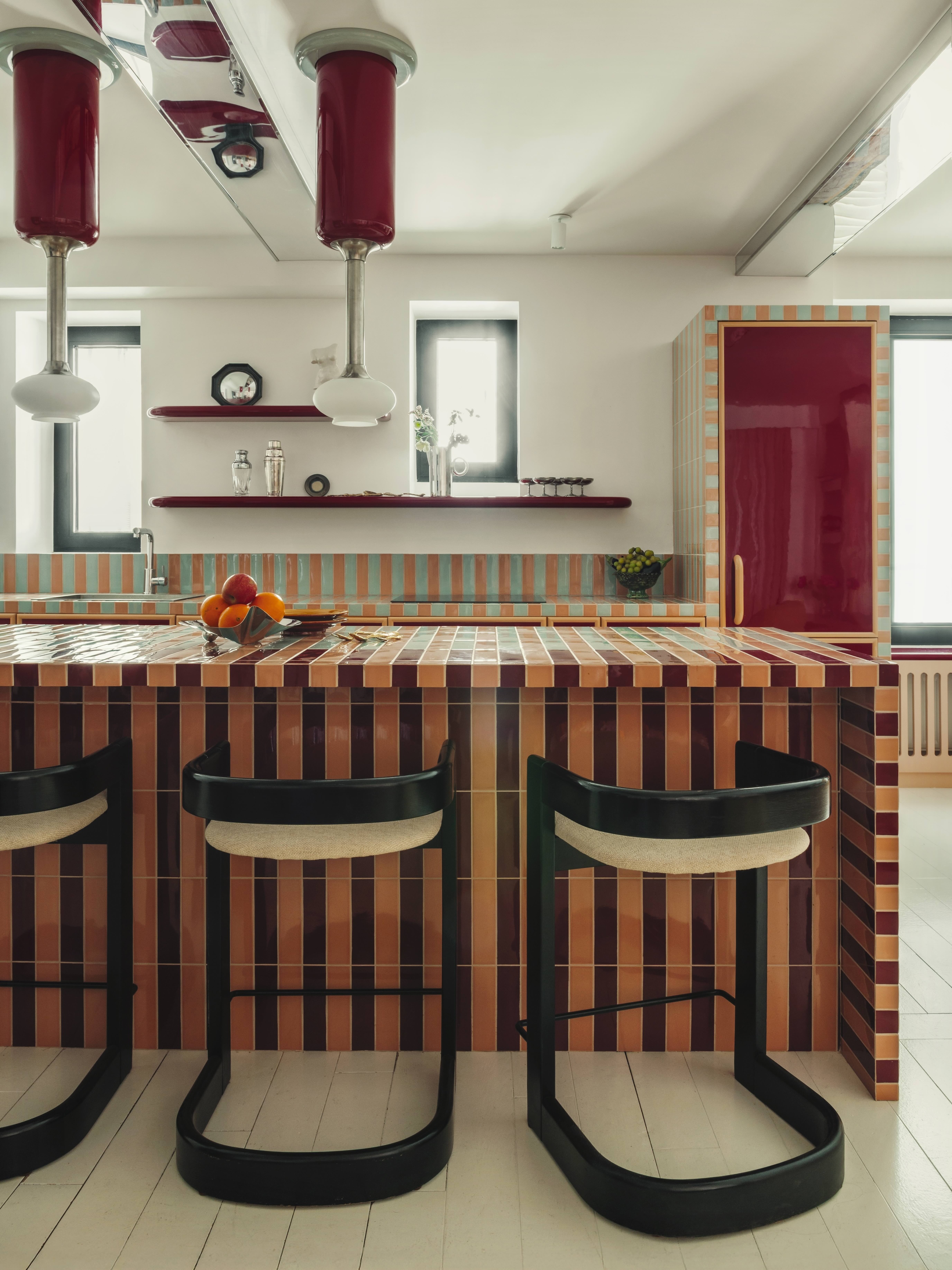 Black lacquered stools rest in front of a tiled kitchen island