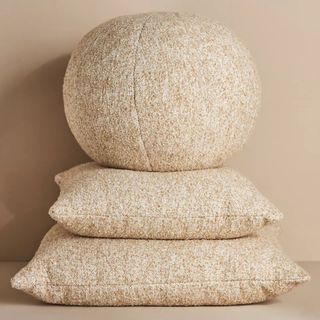 A stack of Anthropologie Cozy Bouclé Pillows