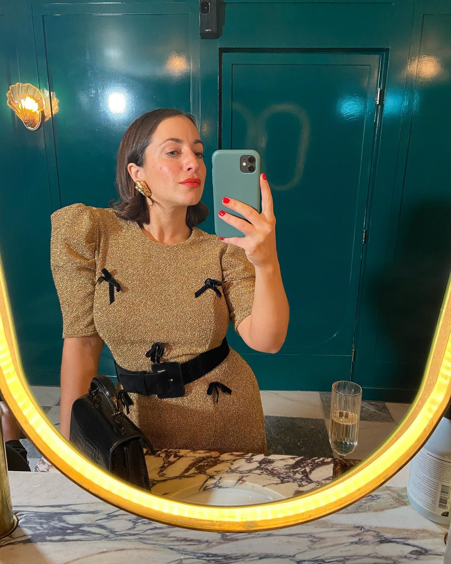 Hannah wears a gold dress with black bow details