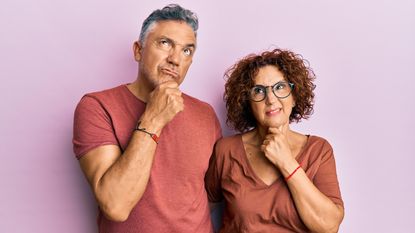 An older couple look into the distance with expressions of doubt.