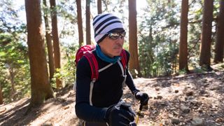 A hiker walks through the trees in a long sleeved base layer