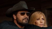 L-R: a close up of Cole Hauser as Rip Wheeler and Kelly Reilly as Beth Dutton standing together and looking forward in Dutton Ranch. 