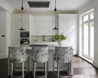 Small white kitchen ideas with white cupboards and an island with grey velvet bar stools
